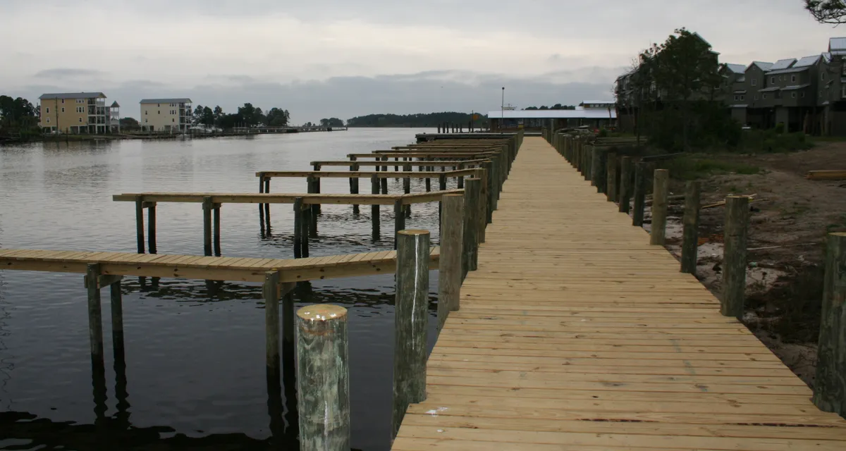 New wooden dock and boardwalk reaching out over calm bay water