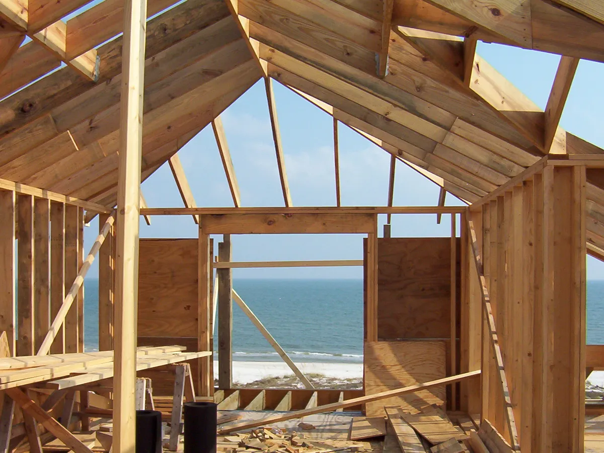 Fresh roof framing of a new beach home with the Gulf of Mexico visible through the open wall