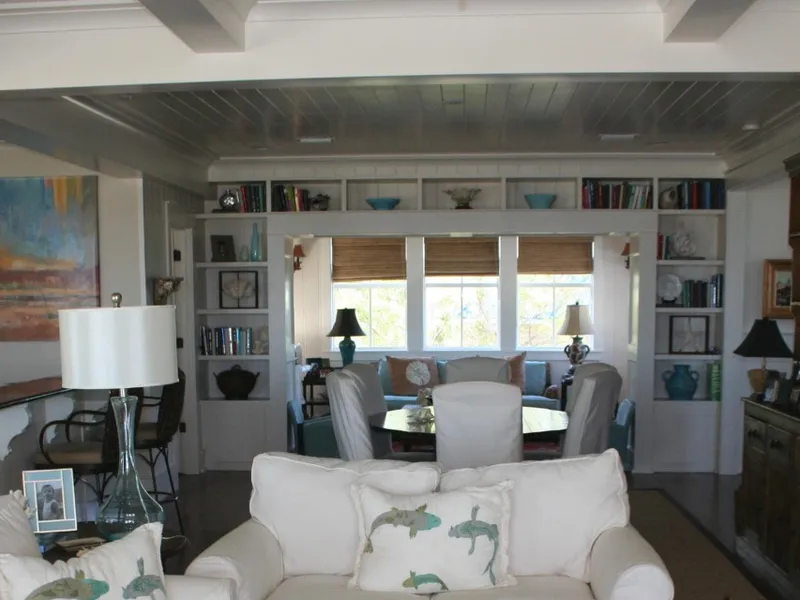 Bright living room with a beadboard ceiling, built-in bookshelves and white sofas